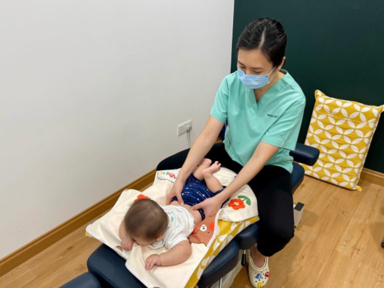 Dr Loh Wei Chee in Welo scrubs, gently checking a baby lying on the treatment table